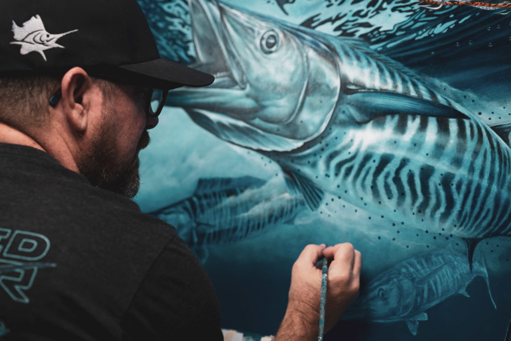 Poster Artist - Dennis Friel working on a painting of a fish